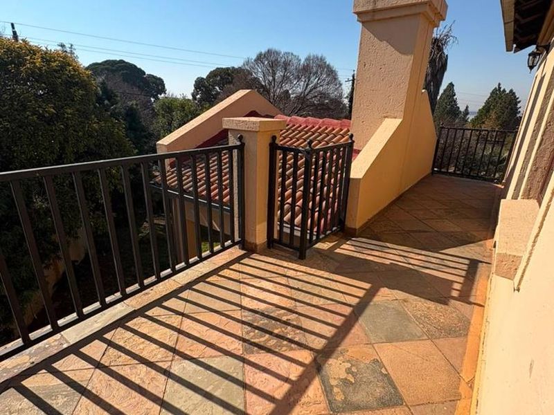 An elevated balcony featuring tiled flooring, a metal balustrade, and a masonry chimney stack, offering an open outdoor space with potential for enhancement.