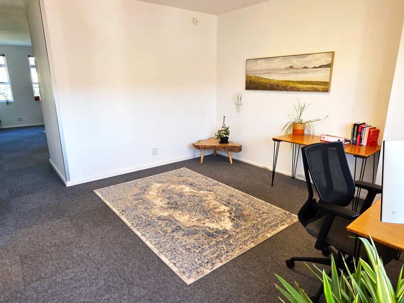 A functional office space featuring neutral walls, carpeted flooring, and an intercom system, providing a clean and professional environment for work.