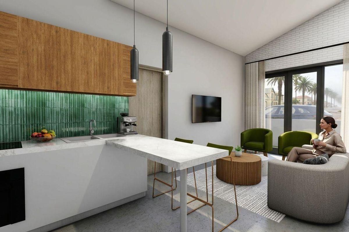 Modern open-plan living area featuring a sleek kitchen with stone countertops, green tiled backsplash, and seamless flow to the outdoor patio area.