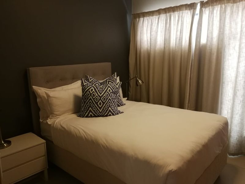 A well-maintained bedroom featuring a dark accent wall and floor-to-ceiling curtains, providing a cozy and modern atmosphere.
