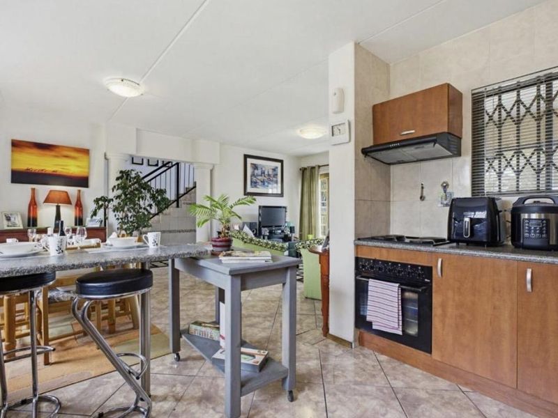 Open-plan kitchen and dining area featuring granite countertops, built-in oven, extractor fan, and tiled flooring, with a breakfast bar for casual dining.