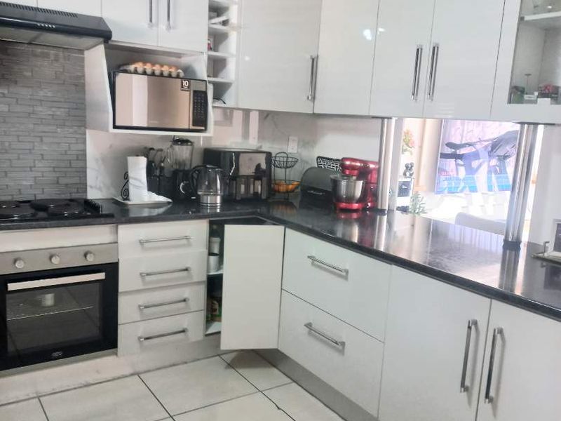 A functional kitchen featuring white cabinetry, dark stone countertops, a gas hob, and an integrated oven with a tiled backsplash.
