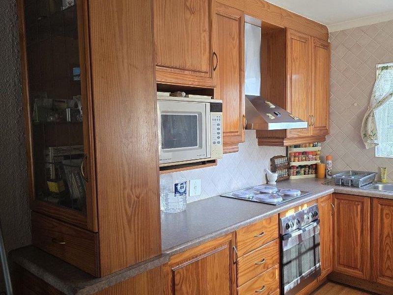 A functional kitchen featuring traditional wooden cabinetry, built-in appliances, a tiled backsplash, and laminate countertops, offering a classic layout with ample storage space.