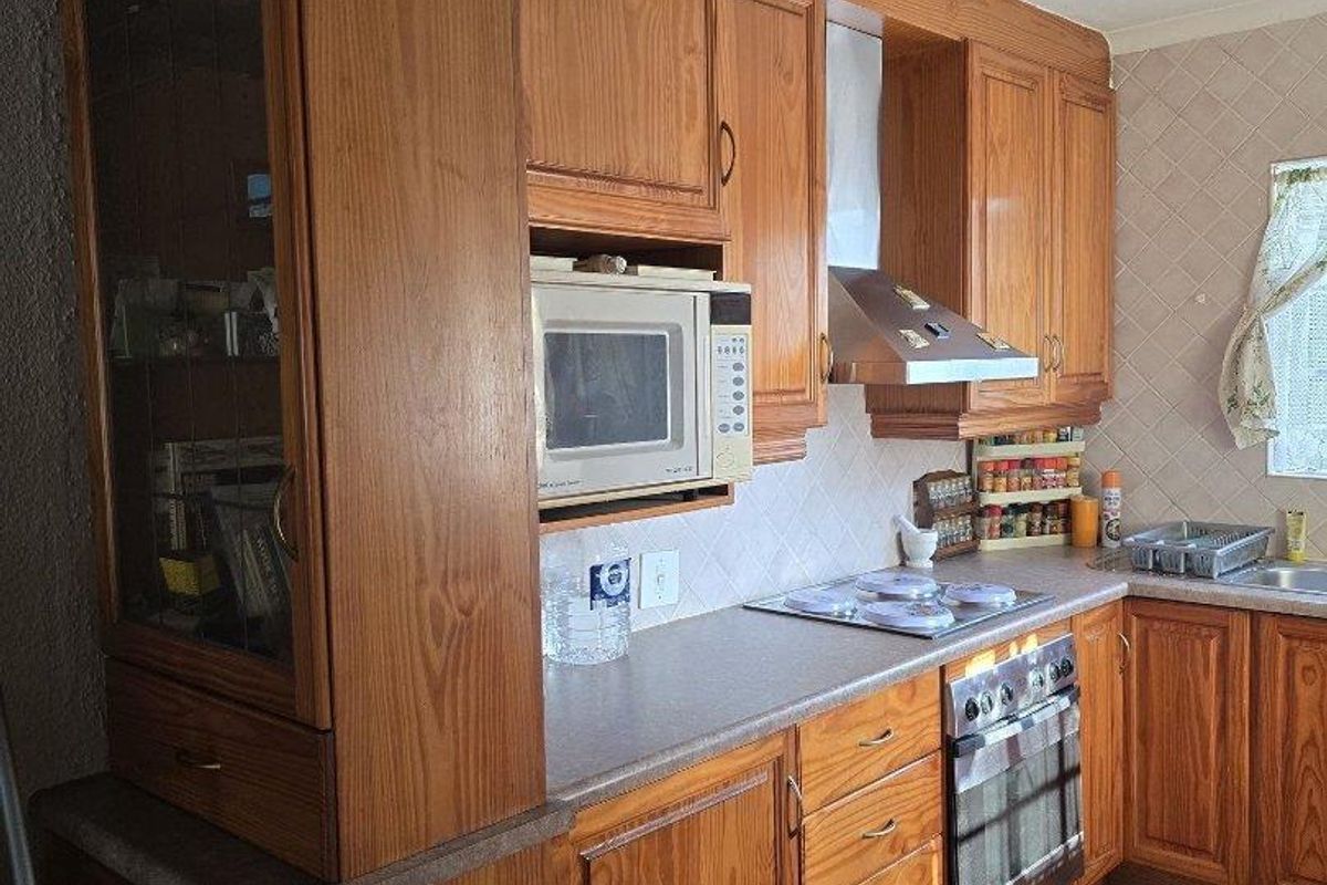 A functional kitchen featuring traditional wooden cabinetry, built-in appliances, a tiled backsplash, and laminate countertops, offering a classic layout with ample storage space.