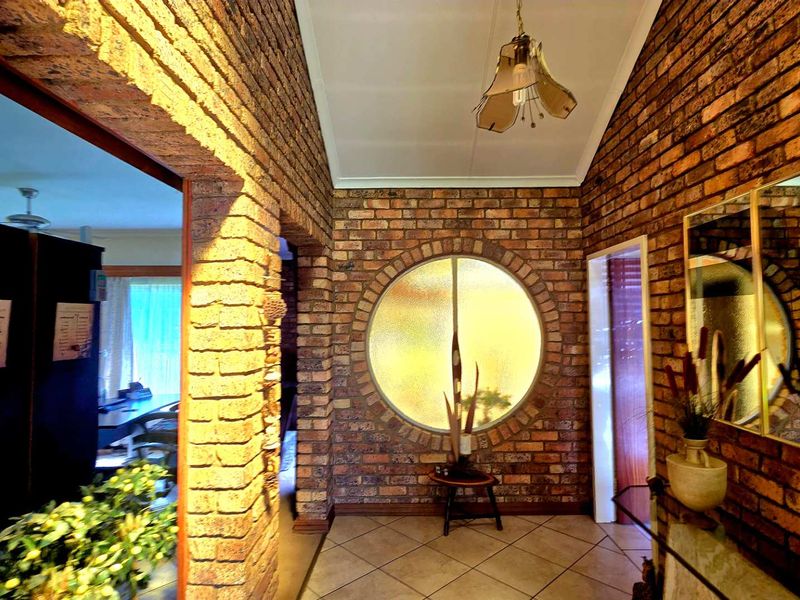 Welcoming entrance hall featuring distinctive exposed brick walls, a unique circular window, and vaulted ceilings, creating a warm and character-filled first impression.