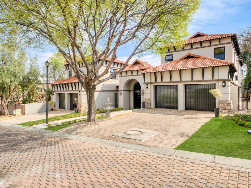A well-maintained double-story residence featuring a paved driveway, double garage, and attractive terracotta roof tiles with stone accents.