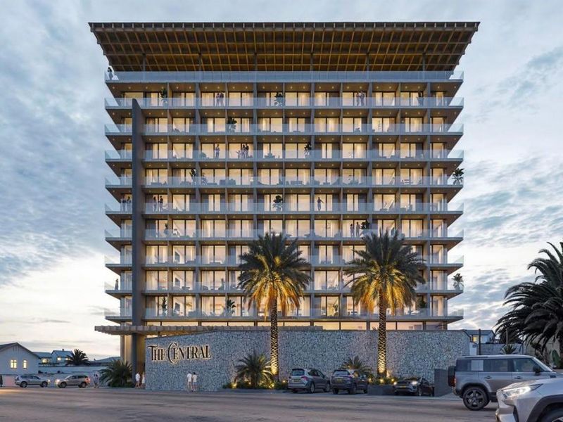 Modern multi-story hotel building featuring a prominent stone-clad entrance, glass-fronted balconies, and a distinctive timber roof structure.