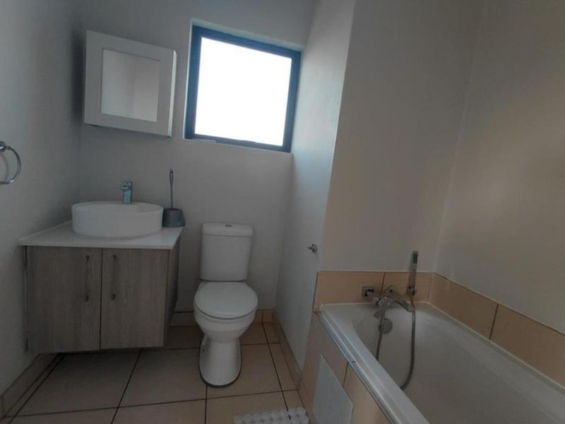 A clean, functional bathroom featuring a modern vanity with vessel sink, a standard toilet, and a bathtub with integrated shower mixer.