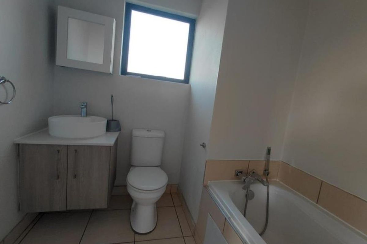 A clean, functional bathroom featuring a modern vanity with vessel sink, a standard toilet, and a bathtub with integrated shower mixer.