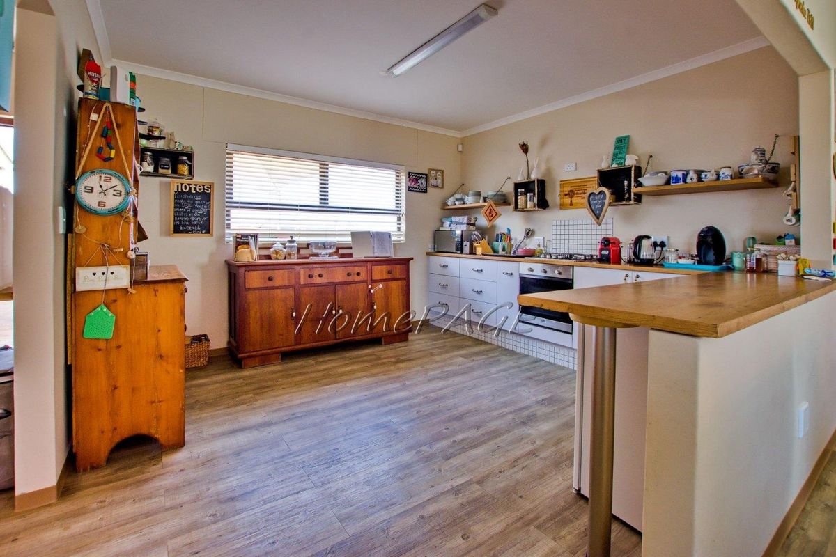 A functional kitchen featuring built-in cabinetry, a fitted oven and hob, and a breakfast bar counter with wood-look flooring.