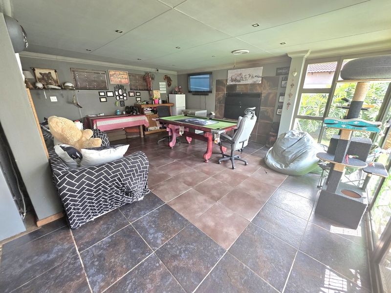 Spacious living area featuring tiled flooring, a built-in fireplace, and large glass sliding doors providing natural light and garden access.