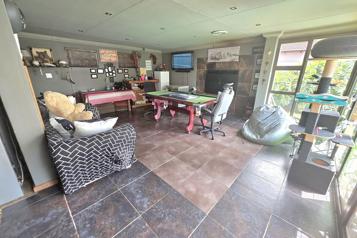 Spacious living area featuring tiled flooring, a built-in fireplace, and large glass sliding doors providing natural light and garden access.