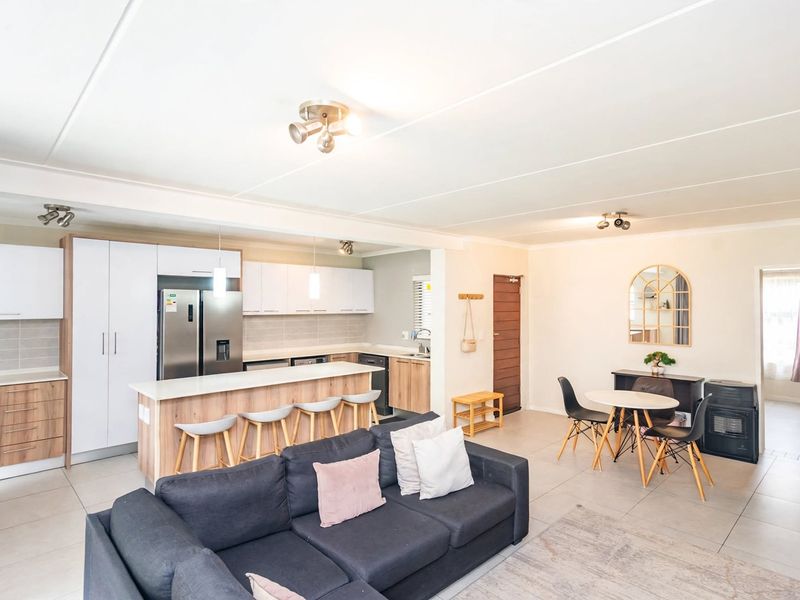 Spacious open-plan living area featuring a modern kitchen with island, ample cabinetry, and tiled flooring, seamlessly flowing into the dining and lounge space.
