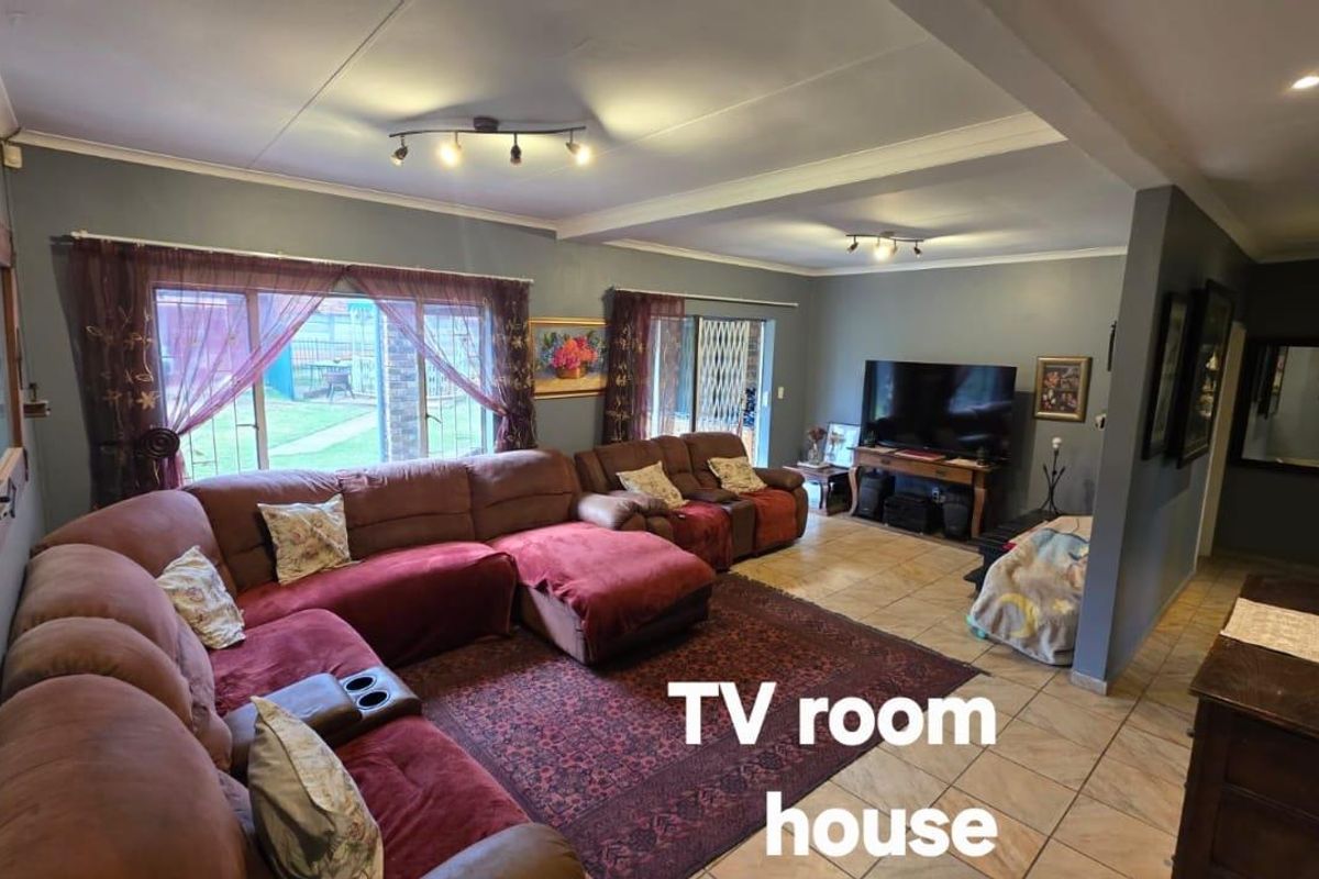 Spacious living room featuring tiled flooring, large sliding glass doors providing garden access, and modern track lighting.