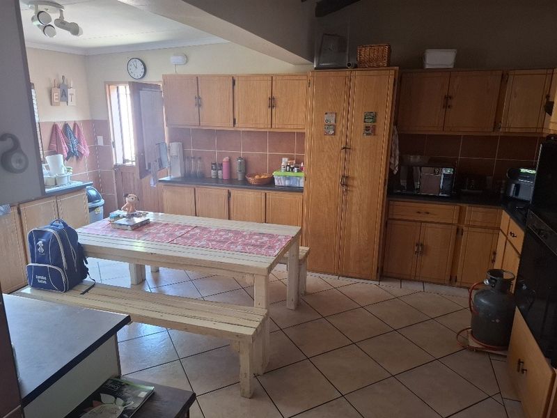 A functional kitchen featuring wooden cabinetry, tiled backsplash, and tiled flooring, offering ample storage space and a practical layout for daily use.