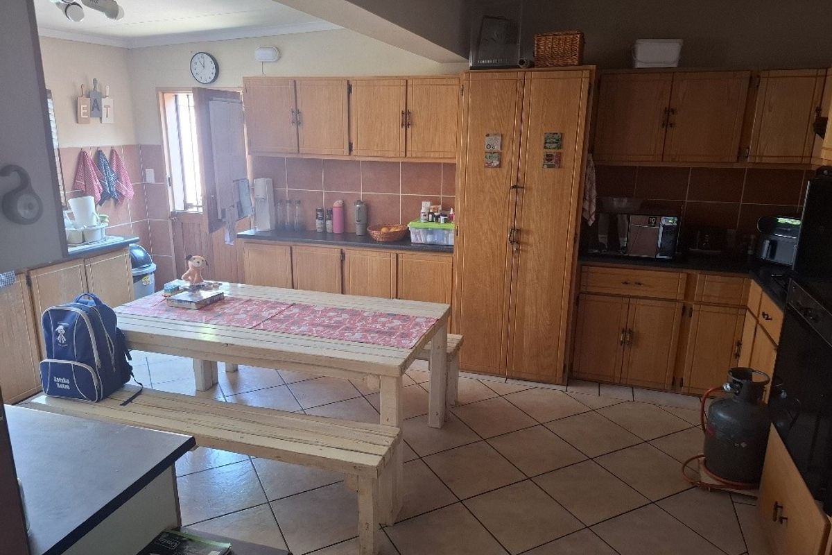 A functional kitchen featuring wooden cabinetry, tiled backsplash, and tiled flooring, offering ample storage space and a practical layout for daily use.