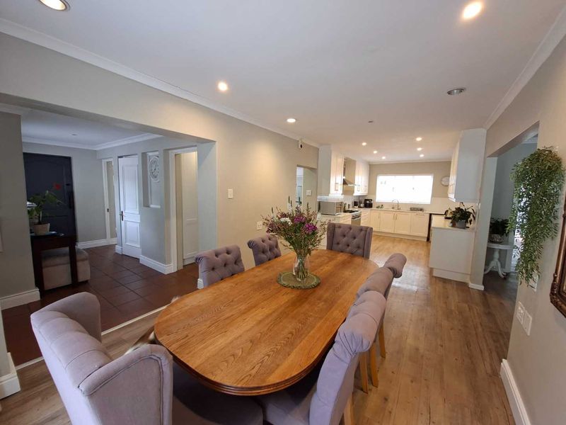 Spacious open-plan dining and kitchen area featuring laminate flooring, recessed lighting, and modern built-in cabinetry with a neutral color palette.