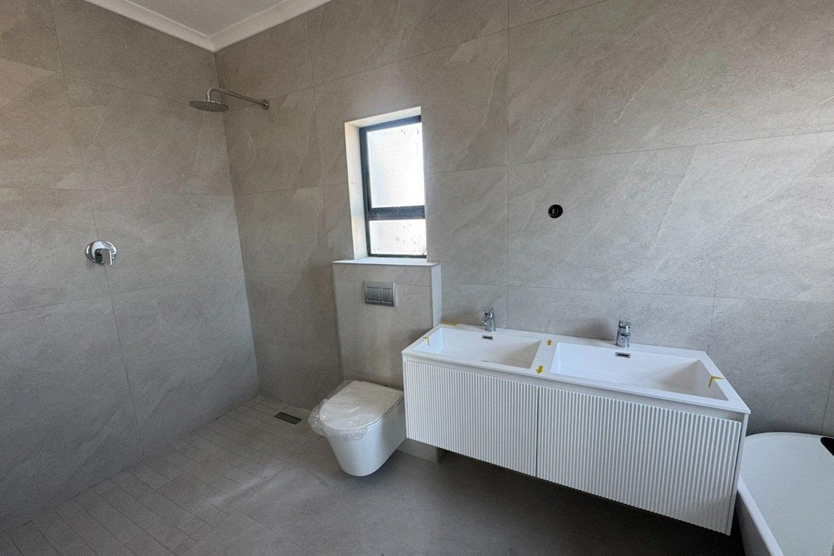 Modern bathroom featuring a wall-mounted double vanity, walk-in shower with rainfall head, and a wall-hung toilet with concealed cistern.