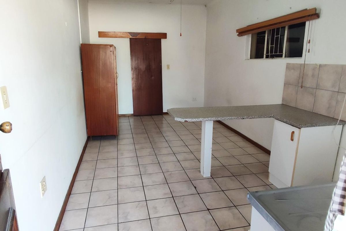 A functional kitchen area featuring tiled flooring, a breakfast bar, and basic built-in cabinetry, offering a blank canvas for potential renovation.