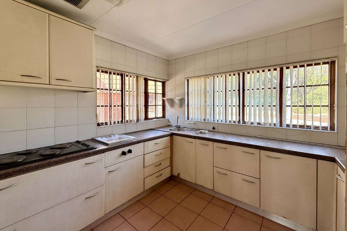 Functional kitchen featuring built-in cabinetry, integrated electric hob, extractor fan, and tiled flooring with ample natural light from multiple windows.