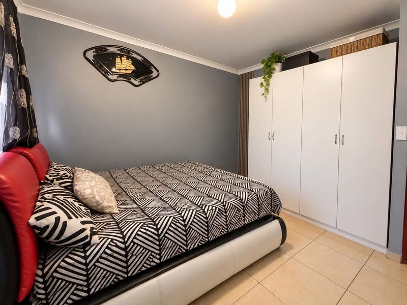 A bedroom featuring tiled flooring, a built-in wardrobe with white cabinetry, and decorative coving.