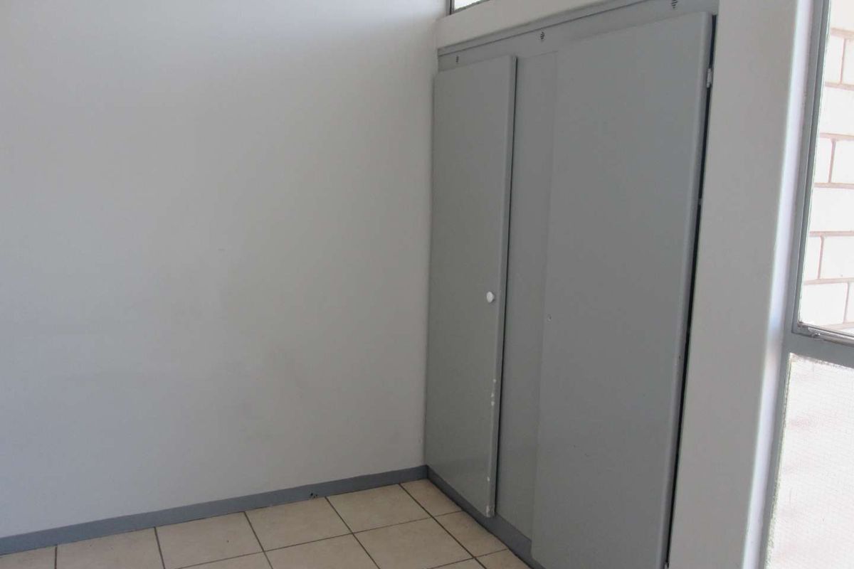 An empty bedroom featuring tiled flooring, a clerestory window, and built-in cupboards with grey finish.