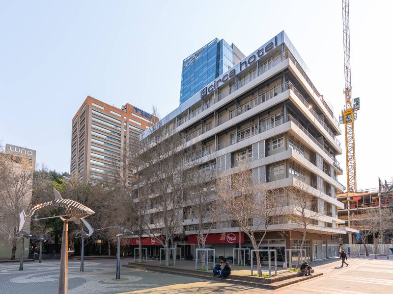 Exterior view of the Circa Hotel building featuring a multi-story facade with balconies and ground-level commercial spaces situated in an urban plaza setting.