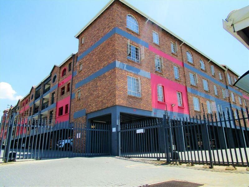 Exterior view of a multi-story apartment complex featuring face-brick facade, secure gated entrance, and undercover parking facilities.