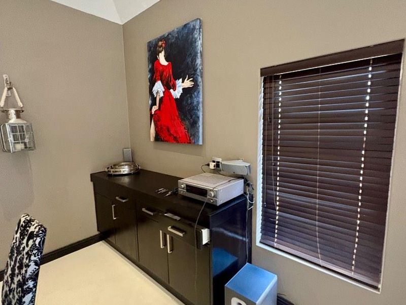 A living area featuring a vaulted ceiling and dark venetian blinds, providing a neutral backdrop for interior styling.