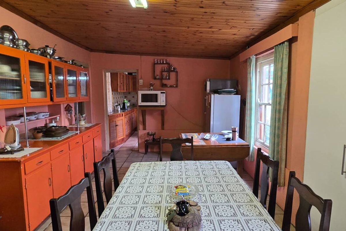 A dated kitchen and dining area featuring timber ceilings, tiled floors, and extensive built-in cabinetry, offering significant potential for a modern renovation.