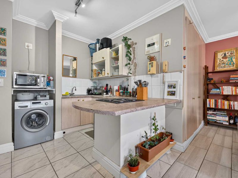 Compact kitchen featuring laminate countertops, a gas hob, built-in cabinetry, and tiled flooring, with an integrated space for a washing machine.