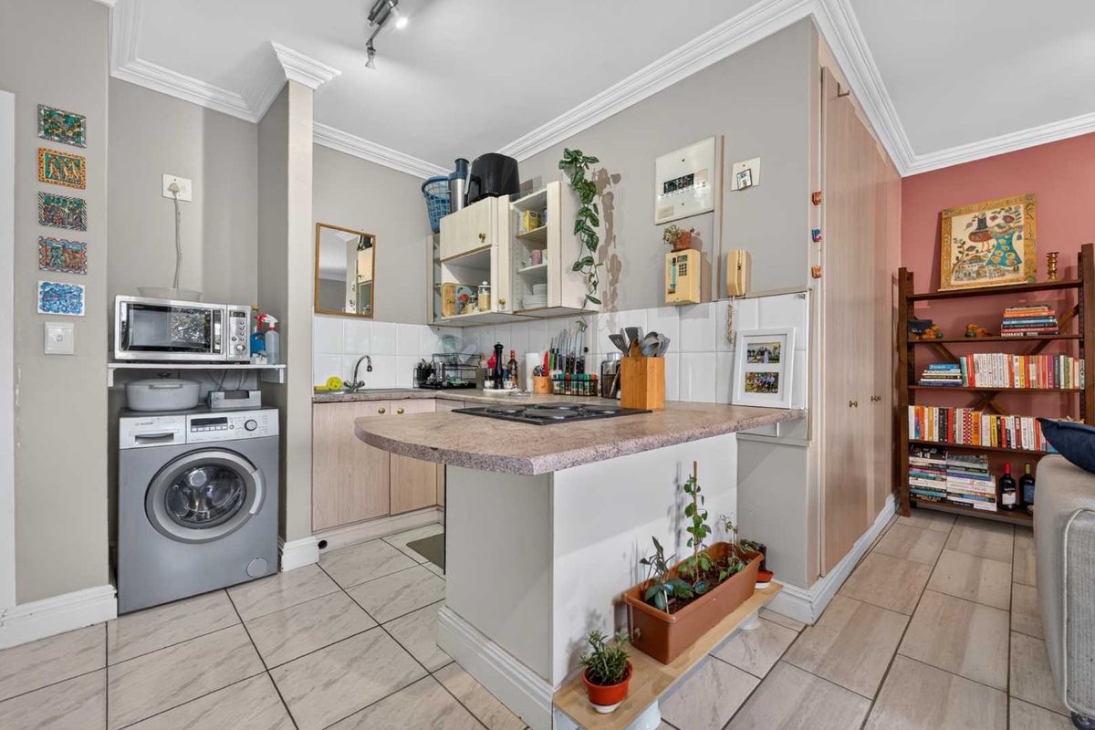 Compact kitchen featuring laminate countertops, a gas hob, built-in cabinetry, and tiled flooring, with an integrated space for a washing machine.
