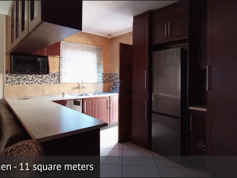 A functional kitchen featuring dark wood cabinetry, tiled backsplash, and a double sink, offering a practical layout for daily meal preparation.