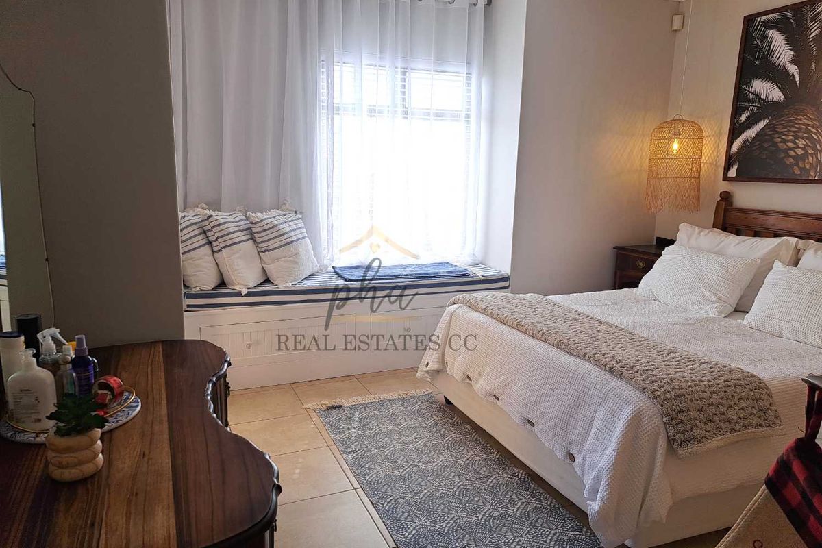 A cozy bedroom featuring a built-in window seat with storage, tiled flooring, and neutral wall finishes.