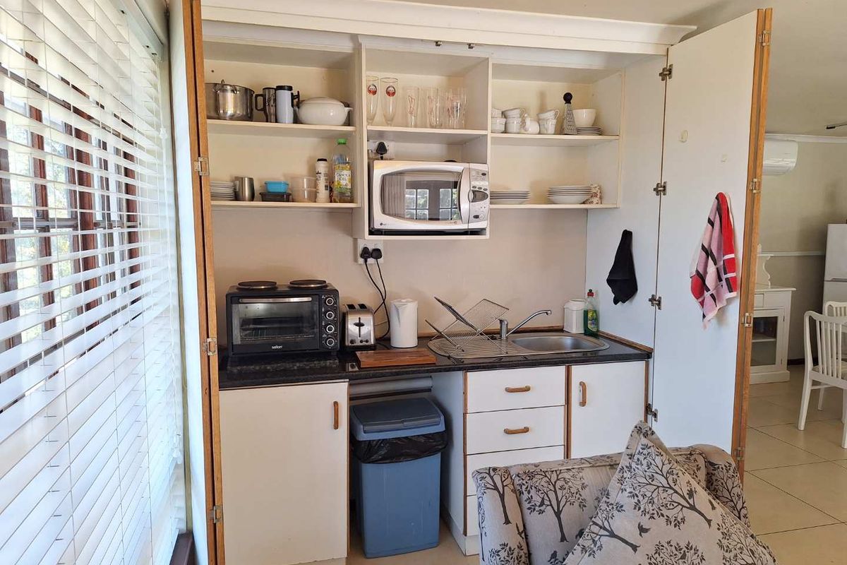 Compact kitchenette featuring built-in cabinetry, laminate countertops, and a stainless steel sink, integrated into a living space.