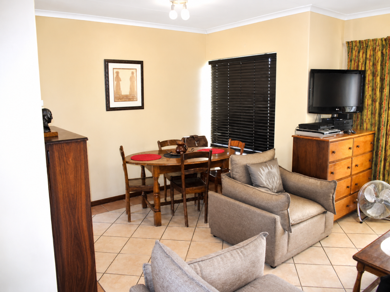A living room area featuring tiled flooring and venetian blinds, providing a functional space for relaxation and dining.