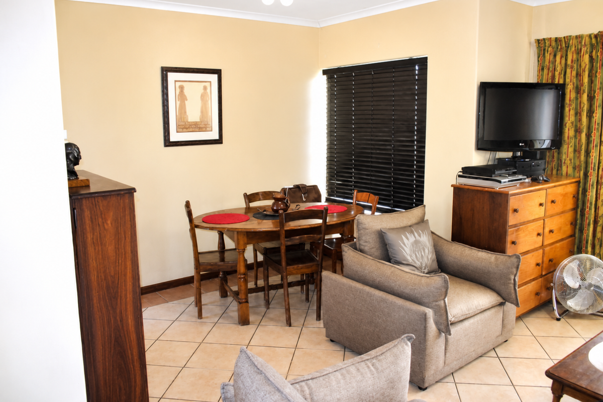 A living room area featuring tiled flooring and venetian blinds, providing a functional space for relaxation and dining.