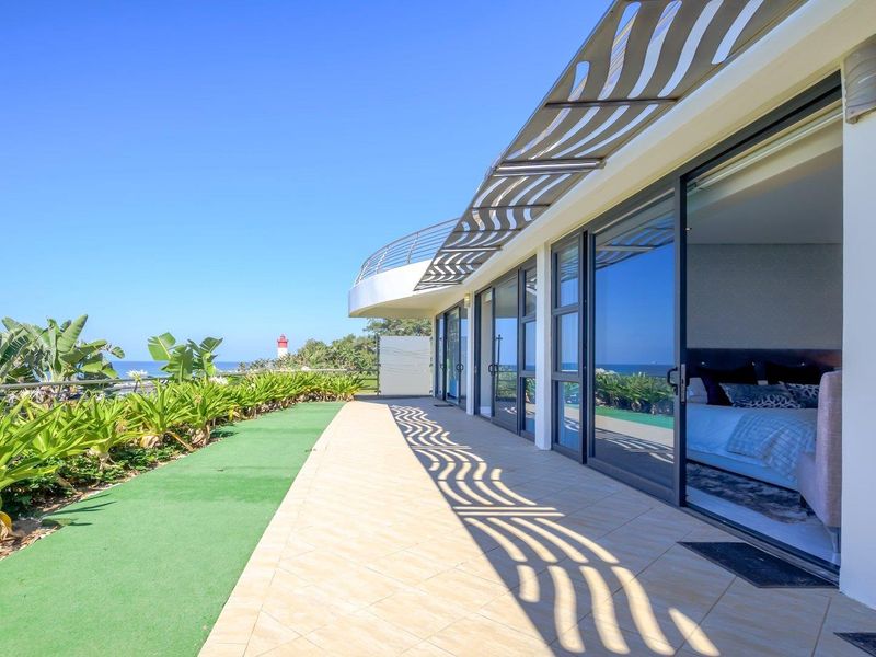 Spacious balcony featuring tiled flooring, a protective pergola, and sliding glass doors providing seamless indoor-outdoor flow with scenic coastal views.