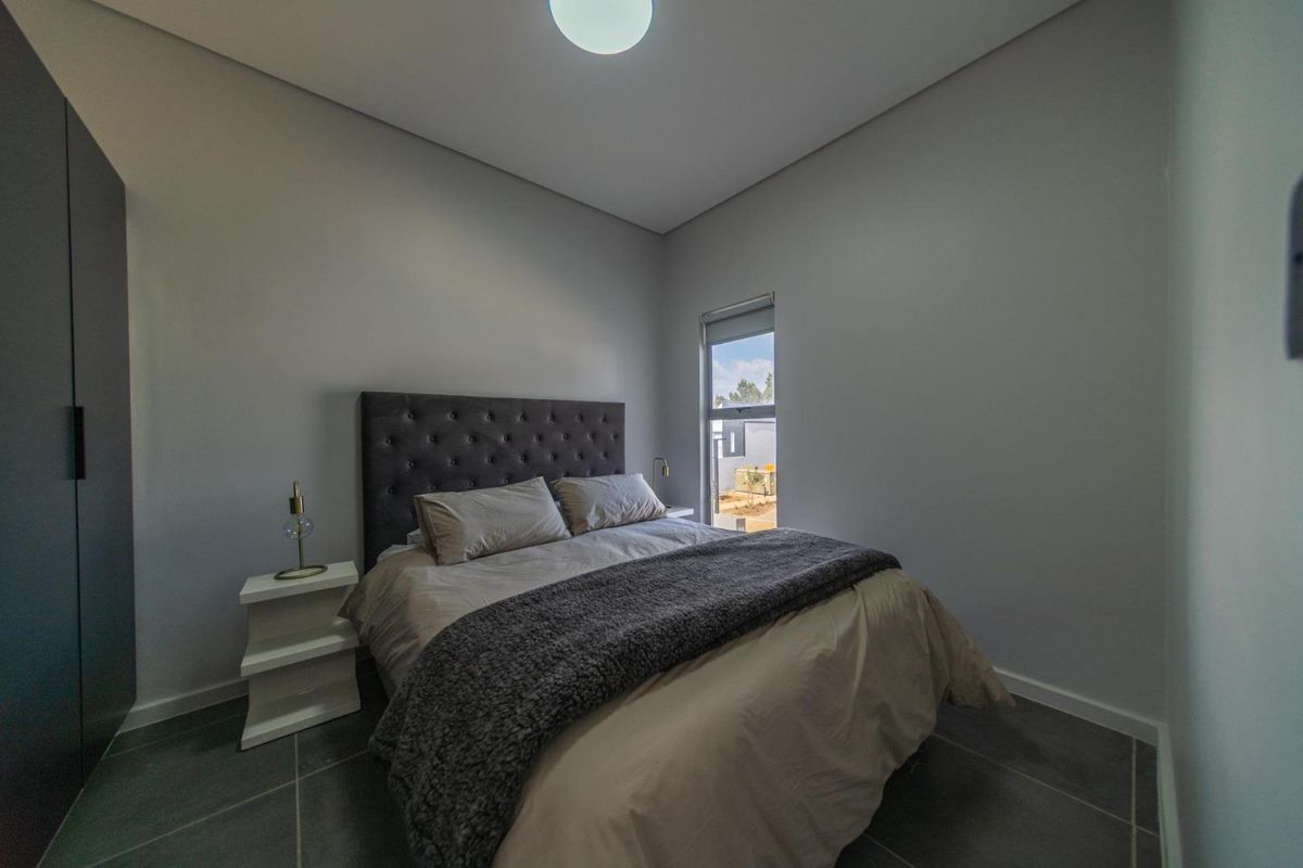 A modern bedroom featuring neutral walls, tiled flooring, and built-in cupboards, offering a clean and contemporary living space.