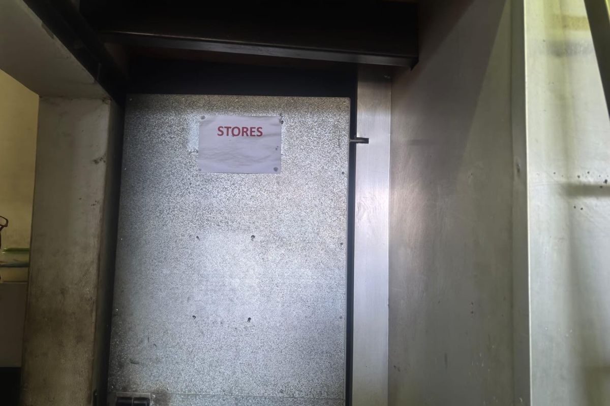 A utilitarian storage area featuring a metal door and exposed structural steel beam, suitable for back-of-house retail operations.