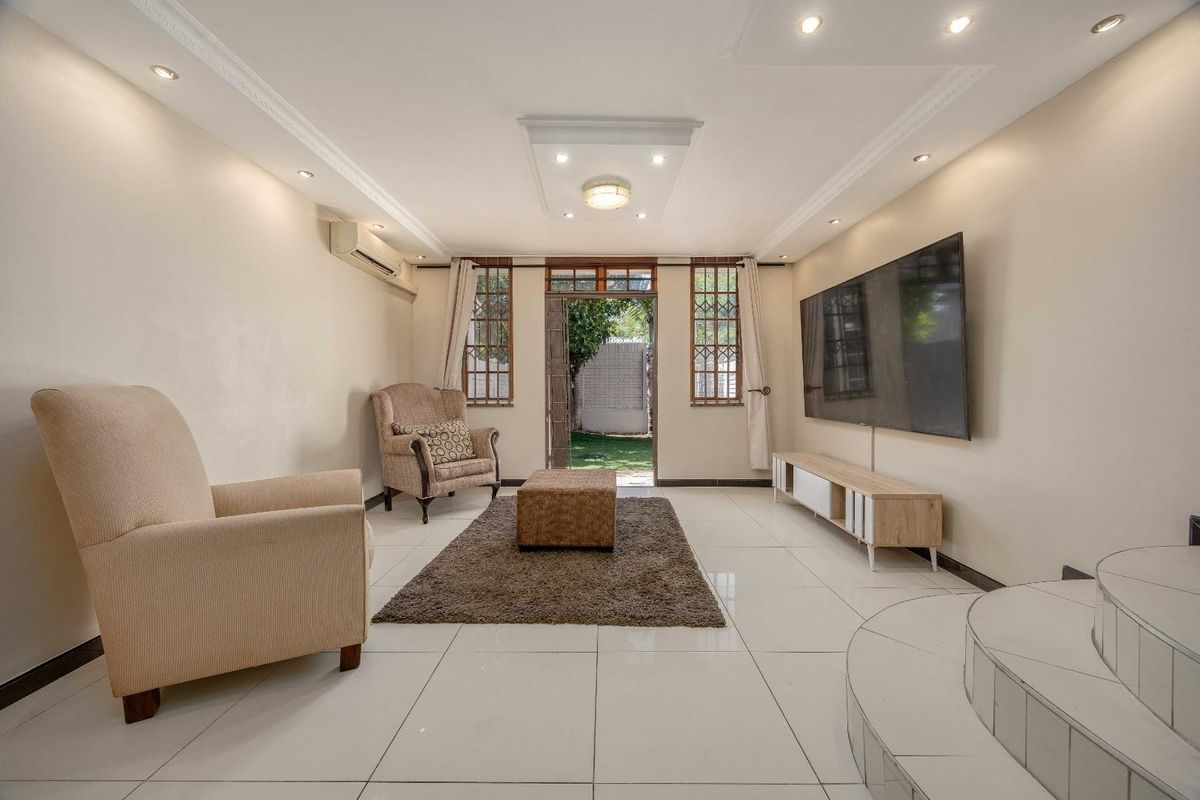Bright living room featuring tiled flooring, recessed ceiling lighting, decorative molding, and direct access to the rear garden area.
