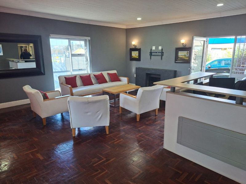 A spacious living area featuring dark parquet flooring, a built-in fireplace, and large sliding glass doors that provide natural light and outdoor access.