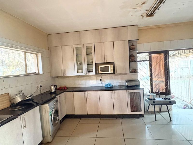 A functional kitchen featuring built-in cabinetry, granite countertops, and tiled flooring, requiring some ceiling repairs to restore its overall condition.