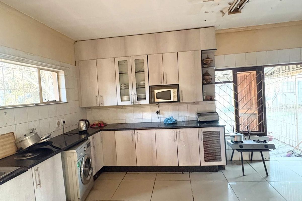 A functional kitchen featuring built-in cabinetry, granite countertops, and tiled flooring, requiring some ceiling repairs to restore its overall condition.