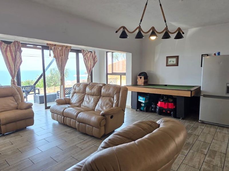 Spacious open-plan living area featuring tiled floors, large sliding doors with ocean views, and integrated kitchen space.