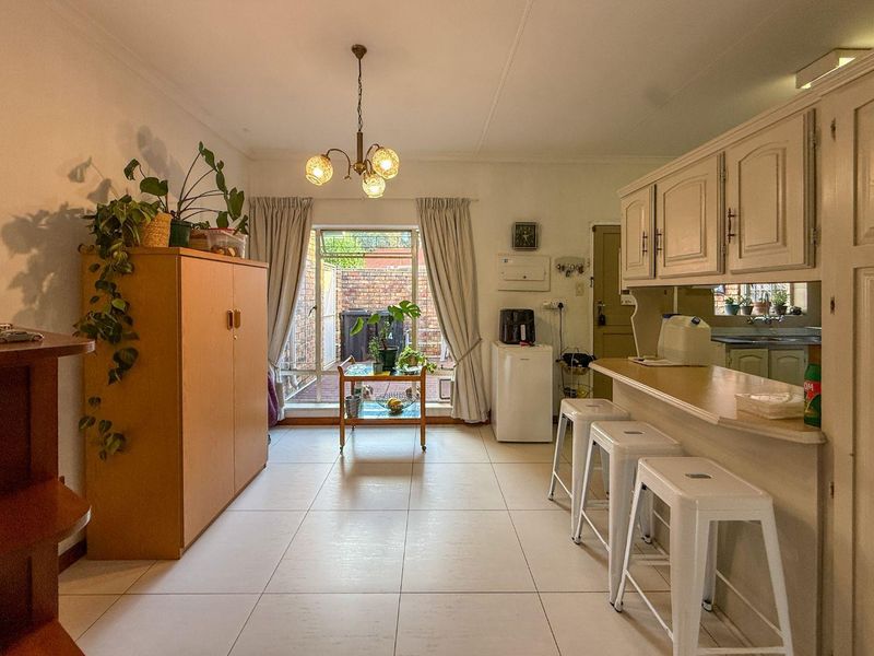 Open plan kitchen and living area featuring tiled flooring, built-in cabinetry, a breakfast bar, and direct access to a rear courtyard.
