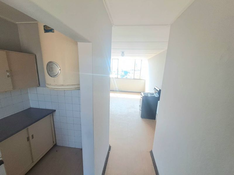 Open plan kitchen and living area featuring dated cabinetry, tiled splashback, and a freestanding stove, offering a blank canvas for renovation.