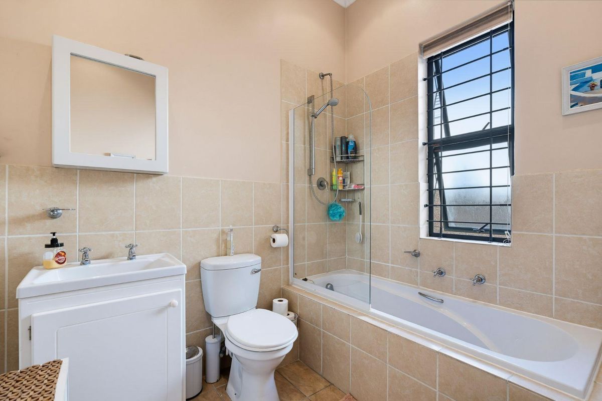 A functional bathroom featuring a built-in vanity, toilet, and a combined bathtub and shower with tiled wall finishes.