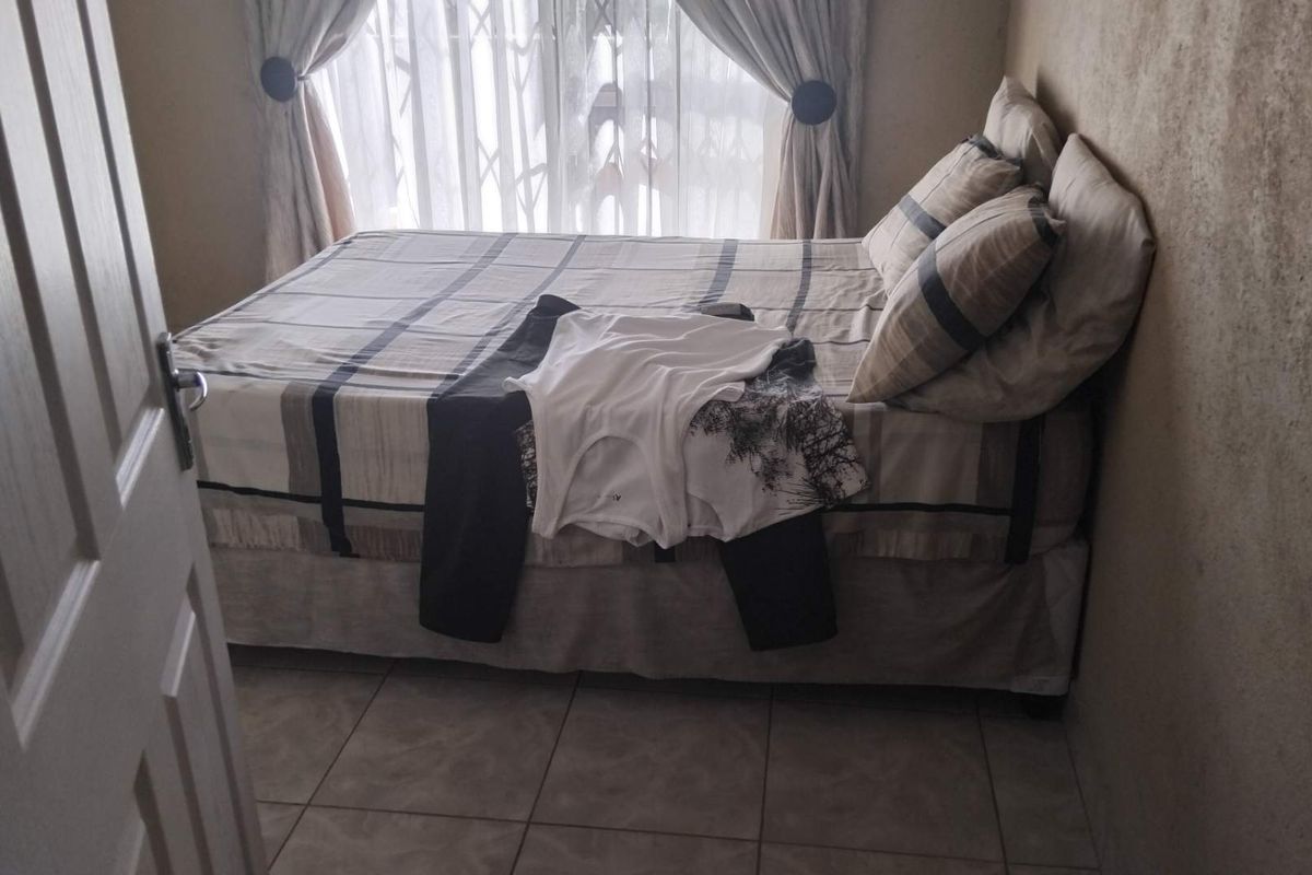 A bedroom featuring tiled flooring and a window with security bars.