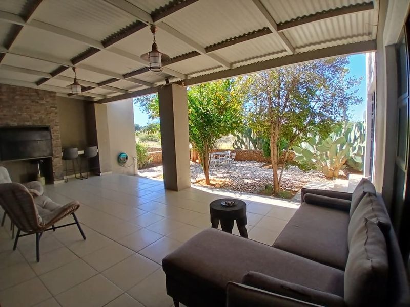 Spacious covered patio featuring a built-in braai, tiled flooring, and direct access to a landscaped garden area, ideal for outdoor entertaining.